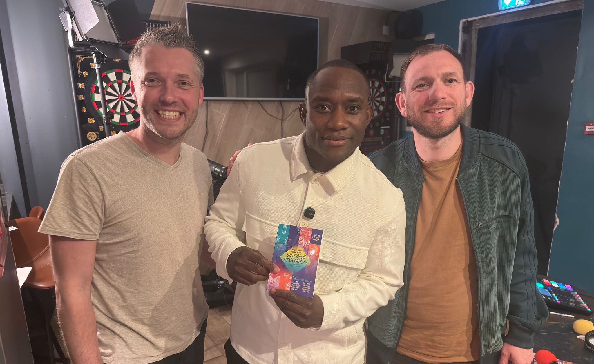 Jérome Laporal, au centre, tient le livre "Victoire éternelle", remis par l'aumônier du sport Joël Thibault, qui est sur sa droite. A sa gauche se trouve l'animateur Joffrey Vanhollemeersh.